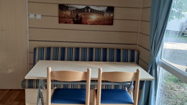 A room with a wooden dining table, two chairs, a bench, and a wall-mounted shelf. - Smart Home Venezia EP Rulantica 15min (Boofzheim)