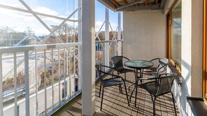 A balcony with a metal railing, a glass table, and two chairs. - Apartamenty Sun & Snow Royal Tulip (Kolobrzeg)