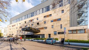 A modern hotel with a prominent 'Royal Tulip Sand' sign, a parking area, and a blue car parked in front. - Apartamenty Sun & Snow Royal Tulip (Kolobrzeg)