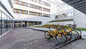 A modern building with a wooden deck, glass doors, and a bike rack with yellow bicycles. - Apartamenty Sun & Snow Royal Tulip (Kolobrzeg)