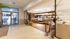 A modern hotel lobby with a reception desk, seating area, and a bar. - Apartamenty Sun & Snow Royal Tulip (Kolobrzeg)