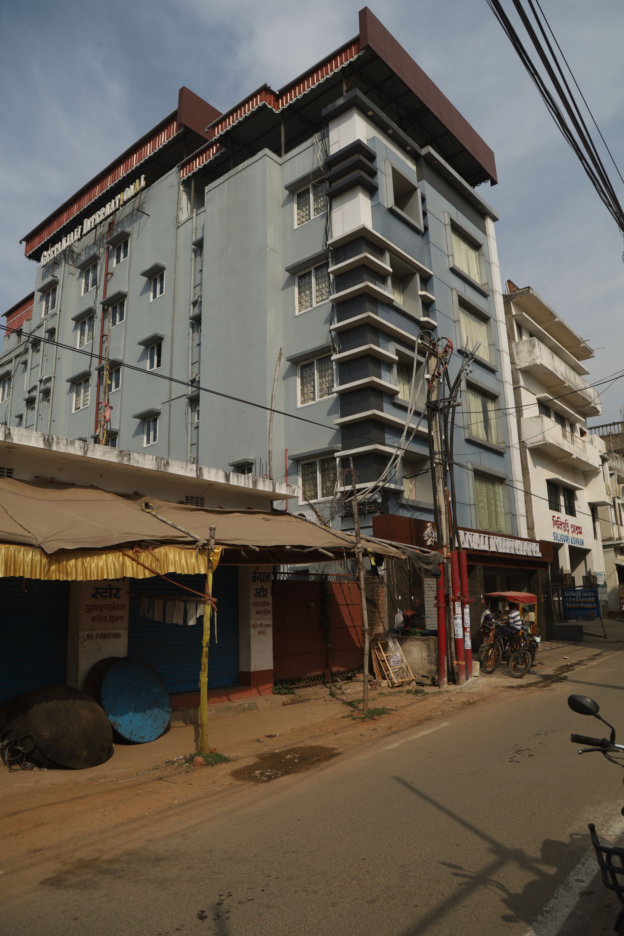 A multi-story building with a sign indicating a hotel. There are bicycles parked outside and a motorcycle on the street.