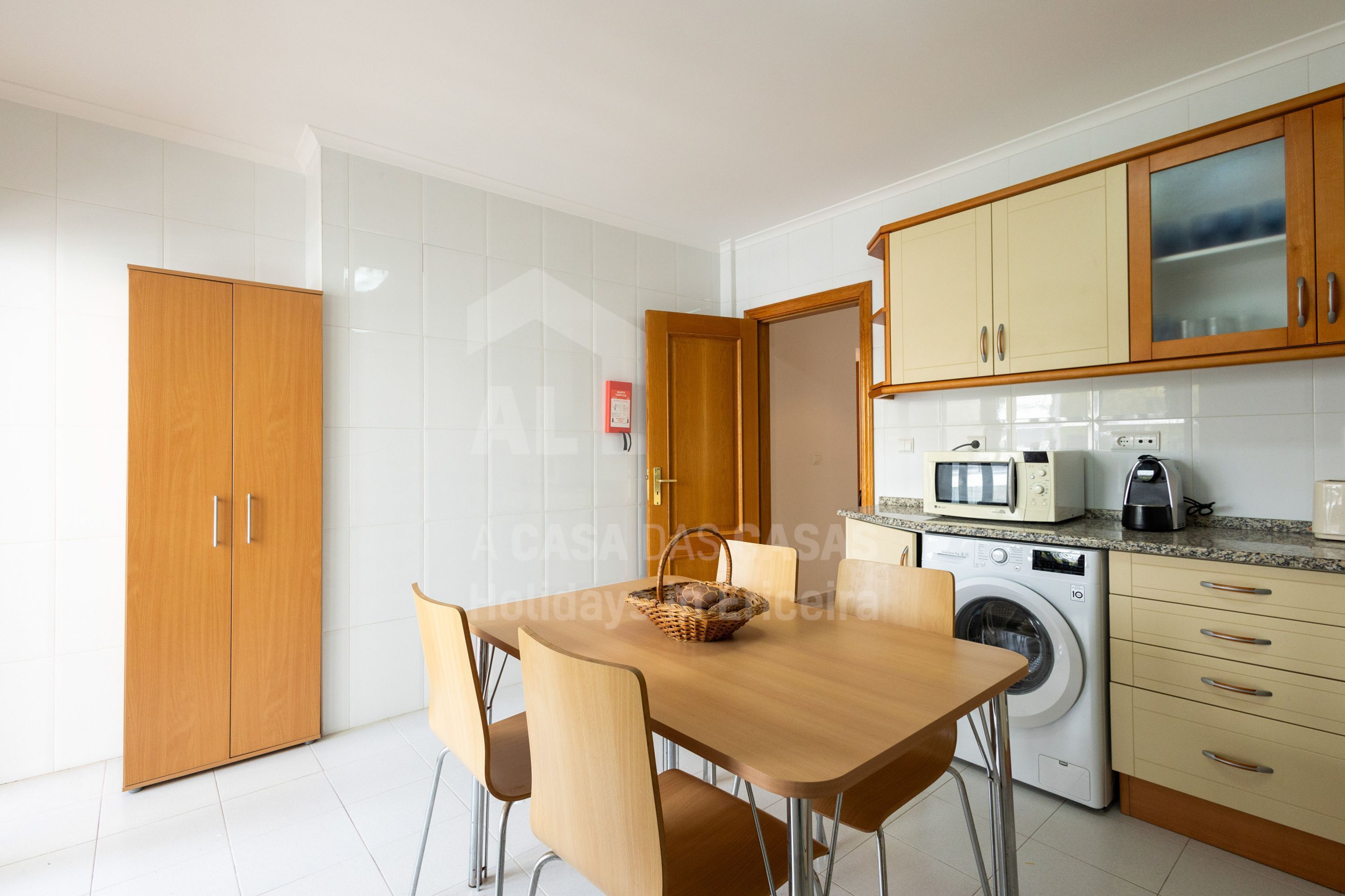 Una cucina moderna con mobili in legno, lavatrice integrata e zona pranzo con tavolo e sedie.