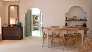 Un coin repas avec une table et des chaises en bois, un miroir et une étagère ornée d’objets décoratifs.