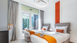 Une chambre d’hôtel avec deux lits, un bureau et une grande fenêtre donnant sur des immeubles.