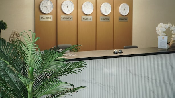 A reception desk with clocks labeled with city names. - Qorasuv hotel (Tashkent)