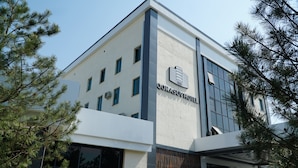 A modern hotel building with a prominent sign reading "QORASIMOV HOTEL". - Qorasuv hotel (Tashkent)