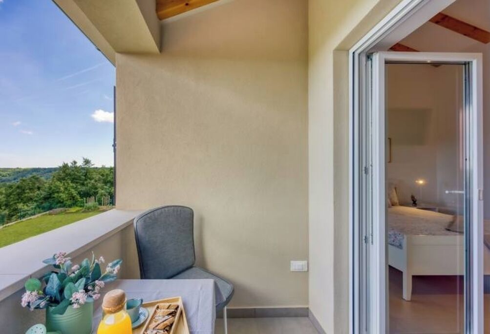 A balcony with a table, a chair, and a view of greenery.