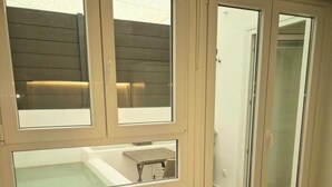 Un dormitorio con cama, ventana con vista a una terraza de madera y puerta corrediza que da a un baño.