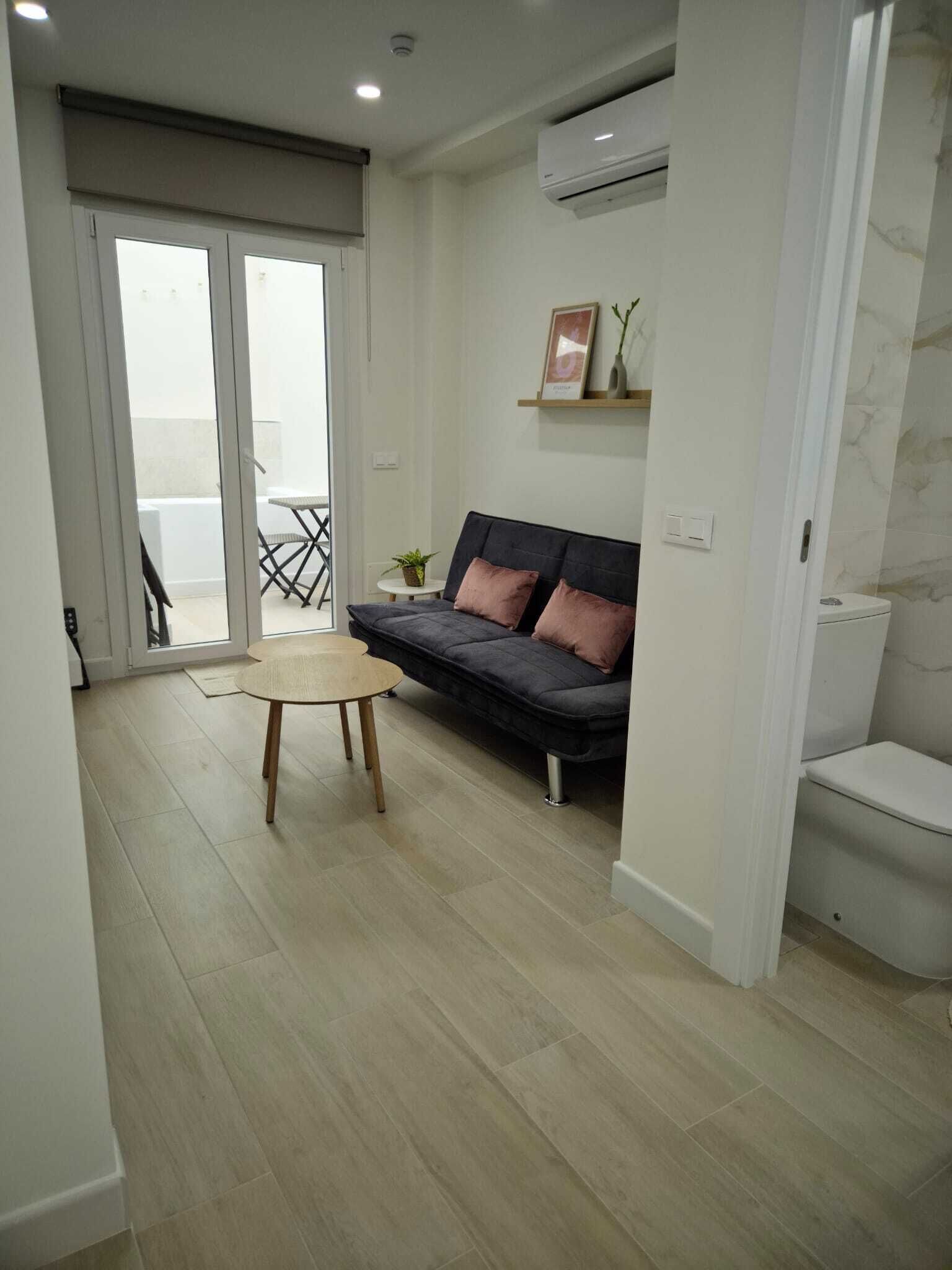 A modern living room with a sofa, a small round table, and a balcony with a chair.