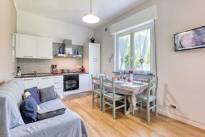 A modern kitchen with white cabinets, a dining table with chairs, and a large window with curtains.