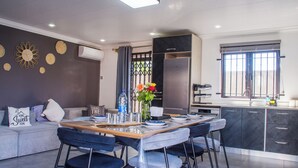 A modern kitchen with a dining area, grey sofa, and decorative wall elements.