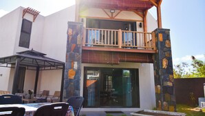 A two-story building with a balcony, outdoor seating, and a covered patio area.