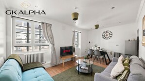 Un salon moderne comprenant un canapé, un téléviseur, un coin repas et une horloge murale.