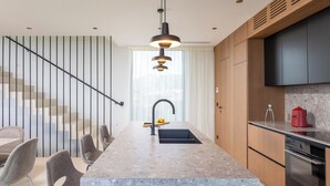 Una cocina moderna con encimera de mármol, horno empotrado y un comedor con sillas.