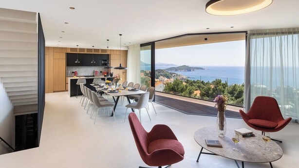 Una sala de estar moderna con comedor, cocina y un balcón grande con vista al mar.