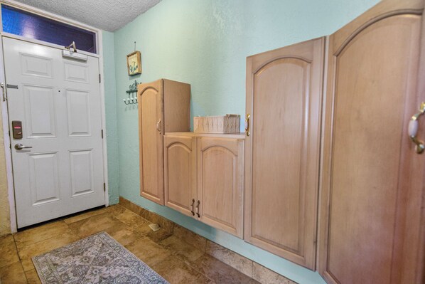 A hallway with a white door, wooden cabinets, and a patterned rug. - Oceanfront Studio Near Pier | Sunrise | Sleeps 2 (Daytona Beach)