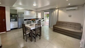 A modern kitchen with built-in appliances, a dining area with a table and chairs, and a living area with a sofa. - Parada Beach Apartamentos (Florianopolis)