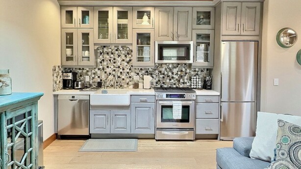 A compact kitchen with grey cabinets, a microwave, a stainless steel refrigerator, and a dishwasher. - Sun 'n Sand Studio at Avila - a perfect beach spot! (Avila Beach)