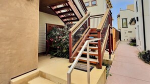 A residential building with a wooden staircase leading to a porch, surrounded by other buildings. - Sun 'n Sand Studio at Avila - a perfect beach spot! (Avila Beach)