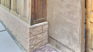 A concrete exterior wall with a wooden door, a metal showerhead, and a small window. - Sun 'n Sand Studio at Avila - a perfect beach spot! (Avila Beach)