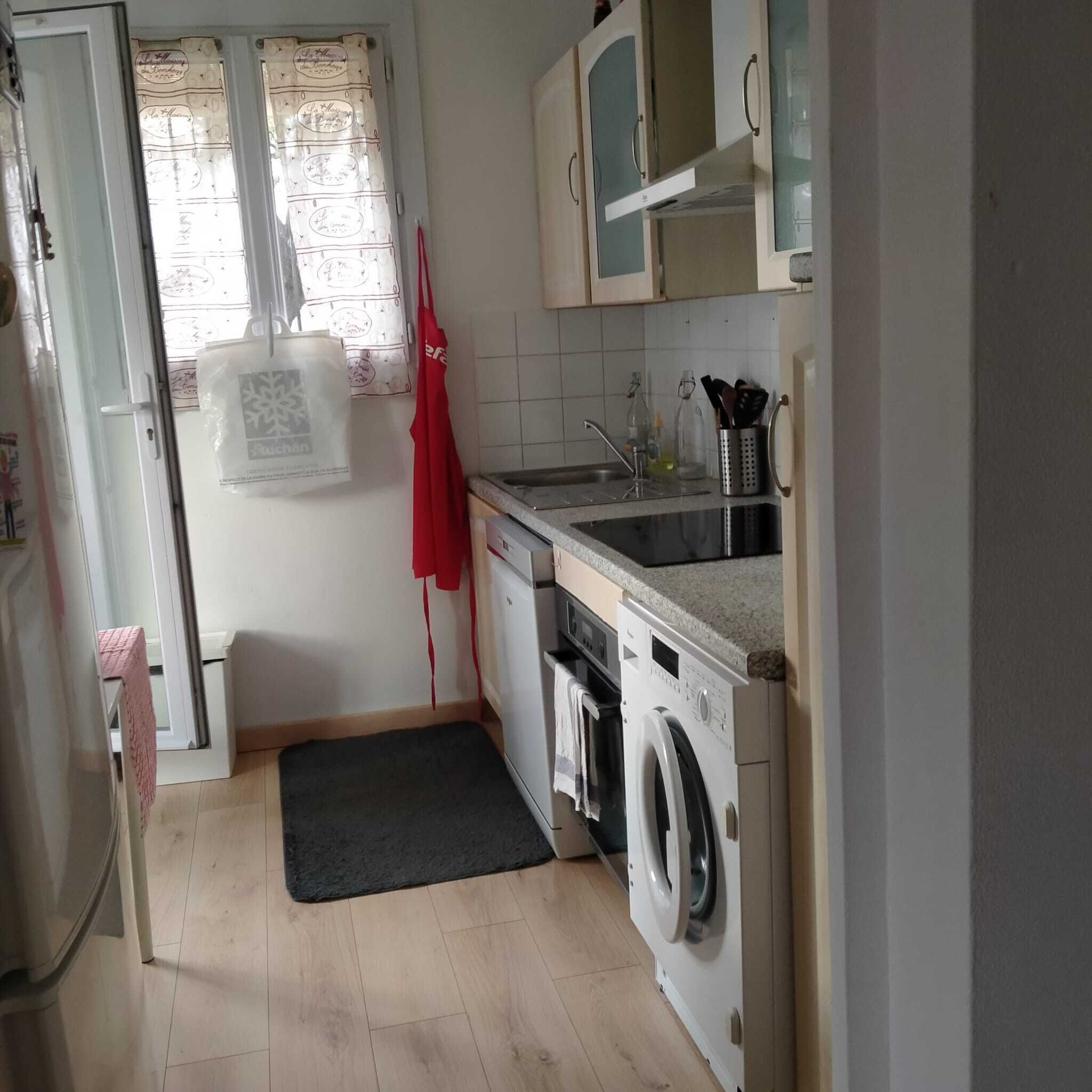 Une cuisine de taille réduite équipée d’un lave-linge, d’un évier et de placards.