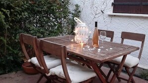 A wooden table with chairs, a wine bottle, and a candle holder. - Charming T3 villa near the sea (Le Pradet)