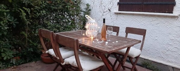 A wooden table with chairs, a wine bottle, and a candle holder. - Charming 3-bedroom villa near the ocean (Le Pradet)