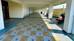 A long corridor with patterned floor tiles, a row of parked motorcycles, and a door on the left. - Kala Retreat (Rishikesh)