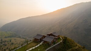Une cabane en bois, dotée d’un toit en pente, entourée de champs en terrasses et de montagnes.
