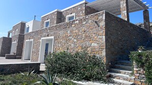 Un edificio de piedra con diseño moderno, que cuenta con un espacio exterior cubierto y una escalera que conduce a la entrada.