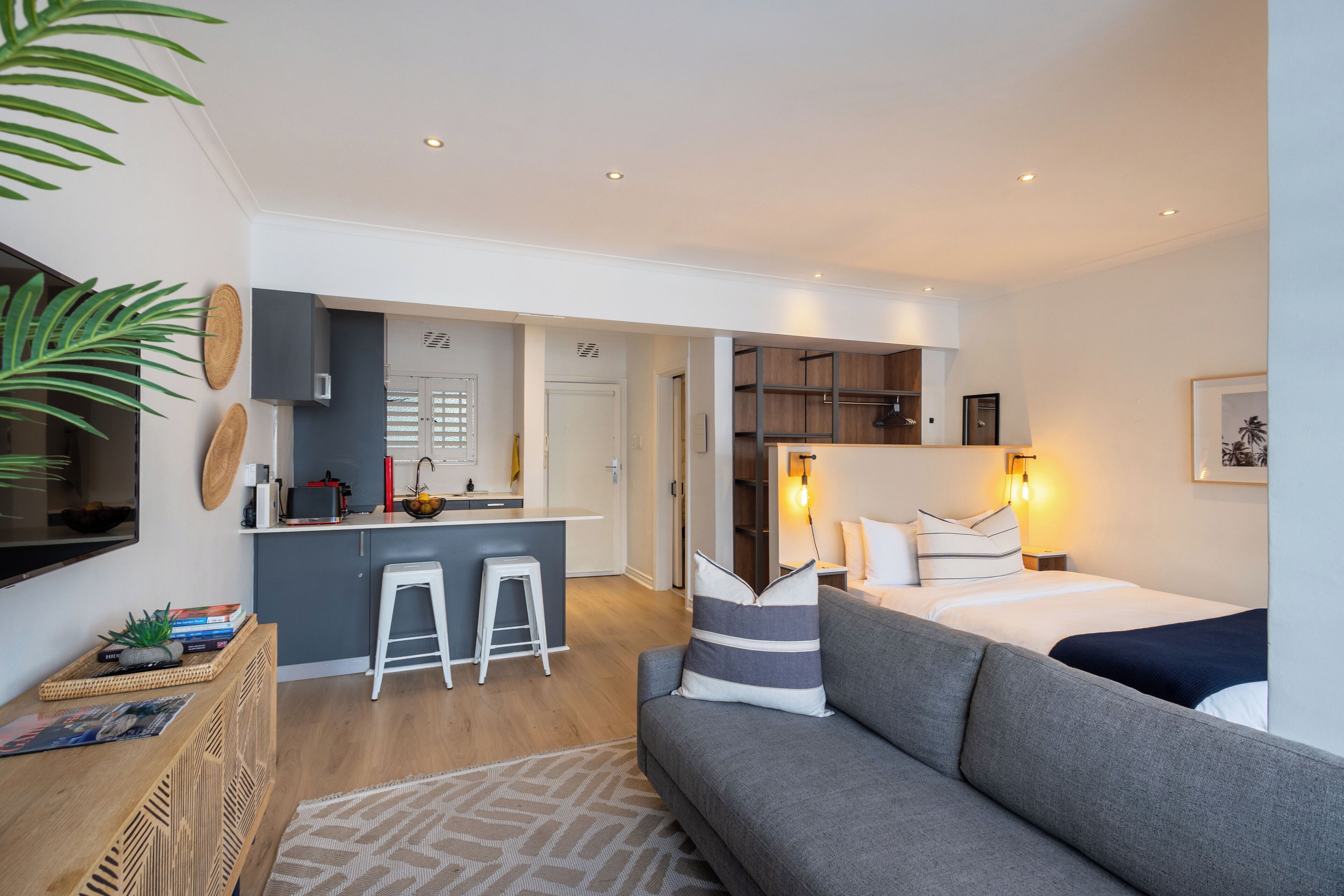 A modern apartment with a kitchen, a dining area, a living room with a sofa, and a bed.