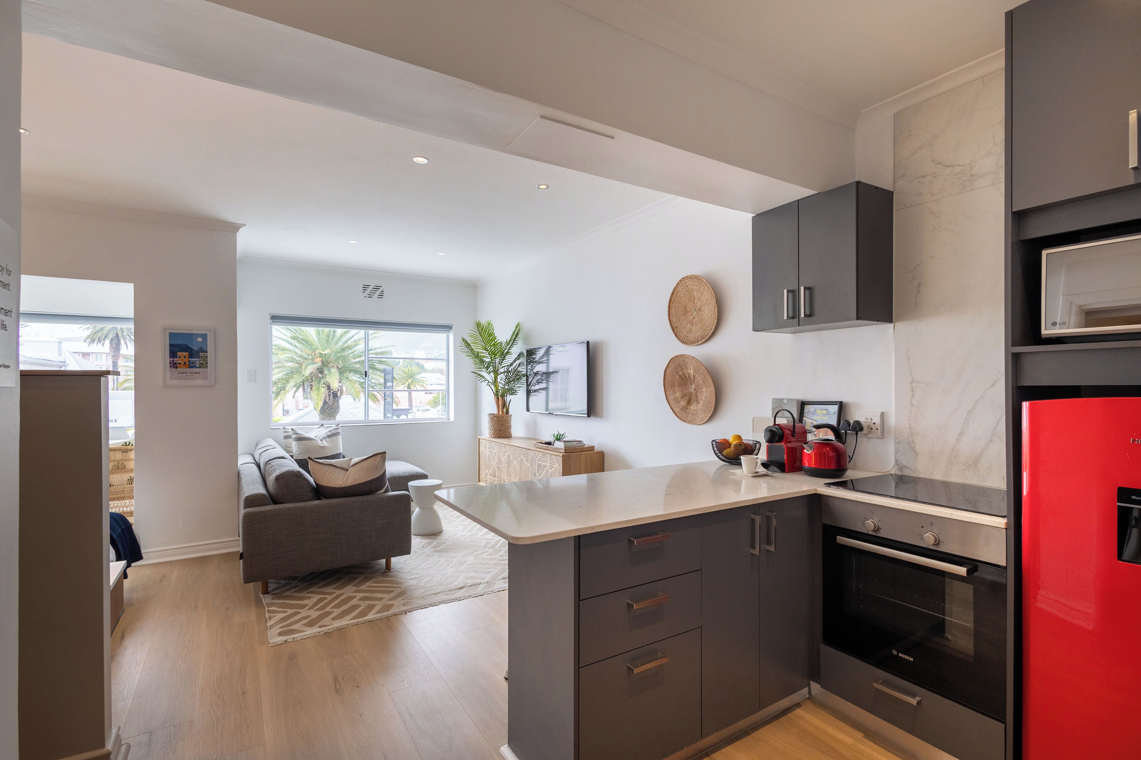 A modern kitchen with dark cabinets, a red refrigerator, and a large island.