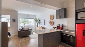 Una cocina moderna con armarios oscuros, un refrigerador rojo y una isla grande.