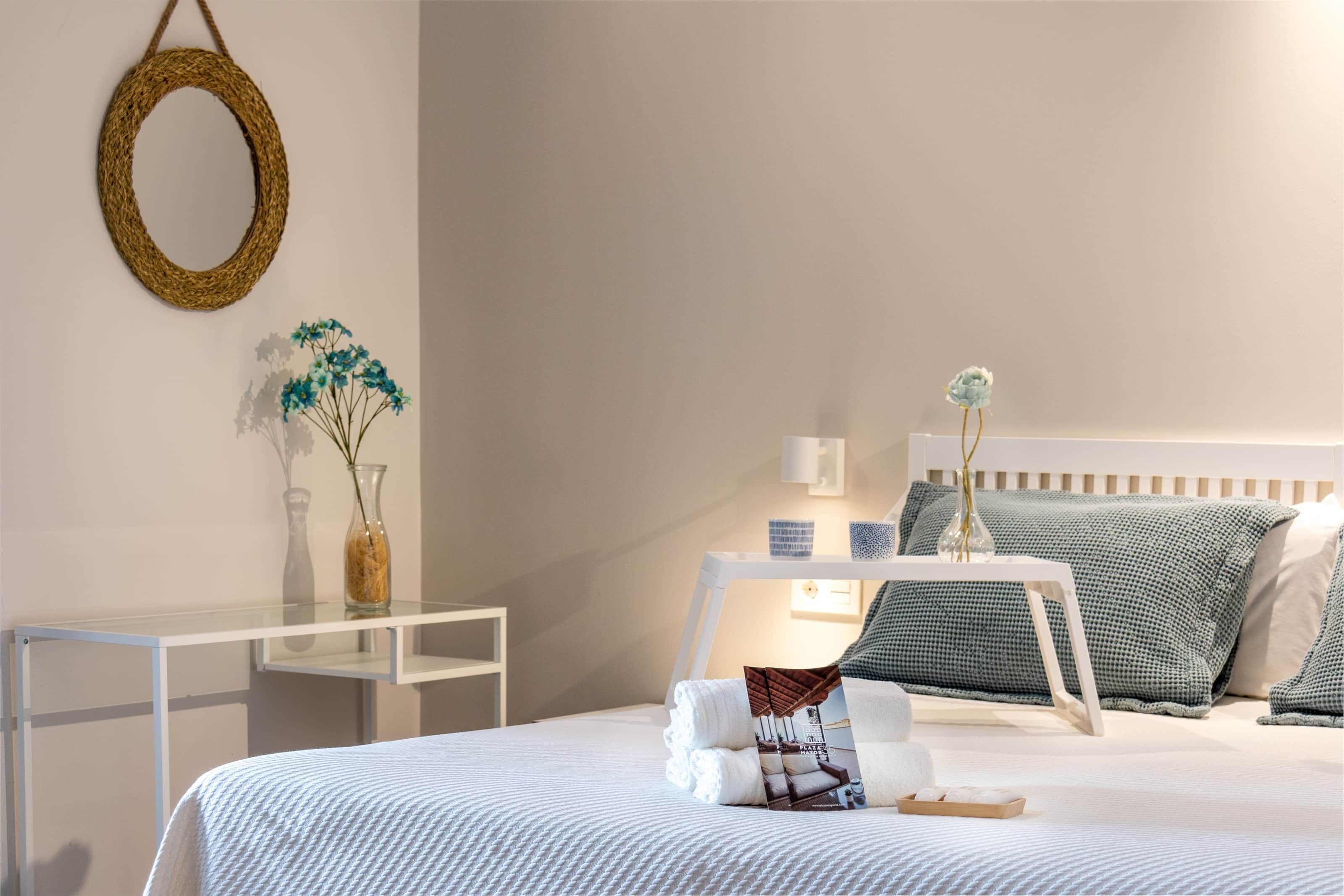 A neatly arranged hotel room with a bed, bedside table, and a small desk.