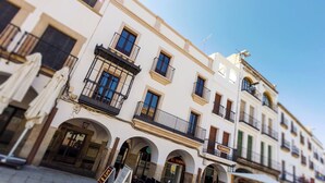 A building with multiple balconies, a cafe with outdoor seating, and a visible storefront with signage. - Apartments Plaza Mayor 35, 105 Family (Cáceres‎)