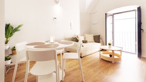 A modern living room with a round dining table, white chairs, a sofa, and a small side table. - Apartments Plaza Mayor 35, 105 Family (Cáceres‎)
