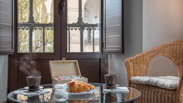 A dining table with a croissant, two cups, and a box of tea. - Apartments Plaza Mayor 35, 105 Family (Cáceres‎)