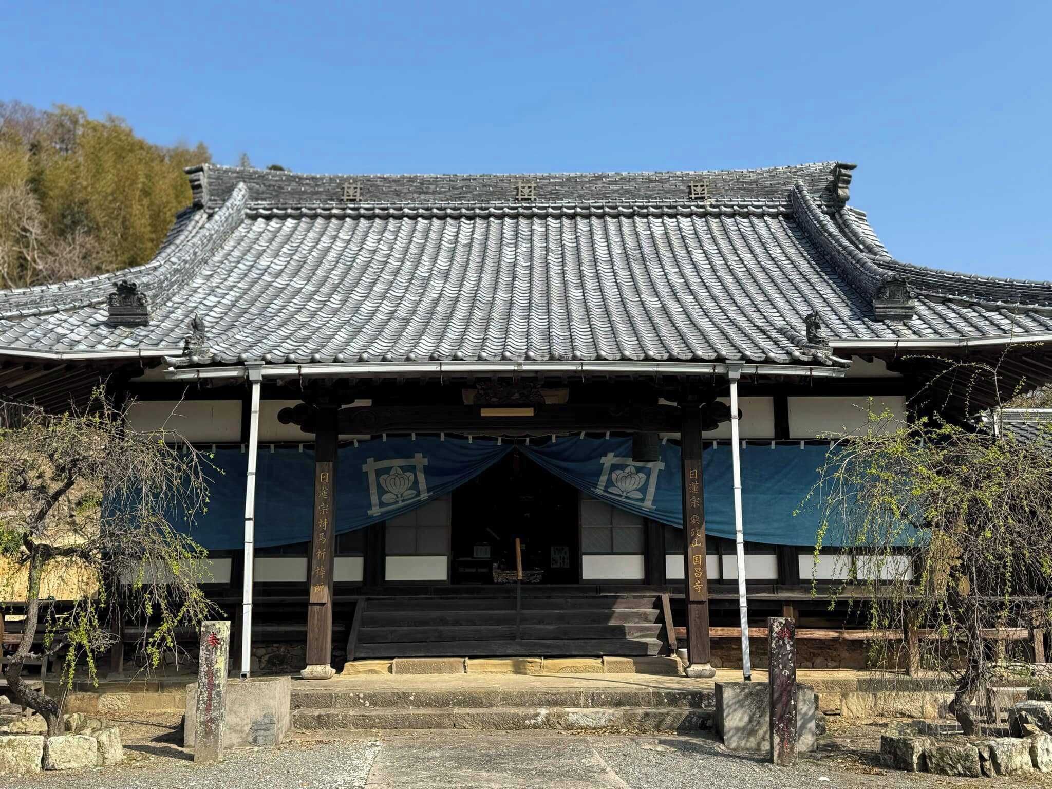 A traditional Japanese building with a tiled roof, wooden beams, and a stone staircase leading to the entrance.