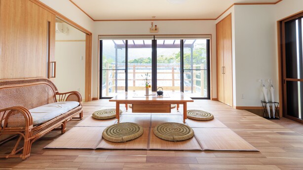 Une pièce de style japonais traditionnel, avec un sol recouvert de tatamis, une petite table en bois et un tapis tissé.