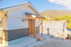 Una casa tradicional japonesa con puerta de madera, un pequeño porche y un farol de piedra.