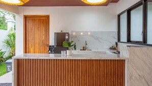 A modern kitchen with a wooden panel backsplash, a marble countertop, and a large window.