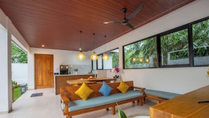 A modern living room with a wooden bench, a dining table, and a kitchen area.