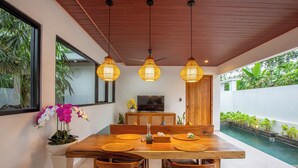 A dining area with a wooden table, chairs, and hanging pendant lights.