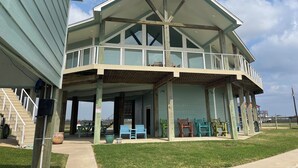 A two-story building with a balcony, outdoor seating, and a view of the beach.