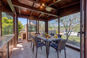 A dining area with a table set for breakfast, surrounded by wicker chairs, and large windows offering a view of the outdoors. - House Stella Nature With Private Pool (Liznjan)