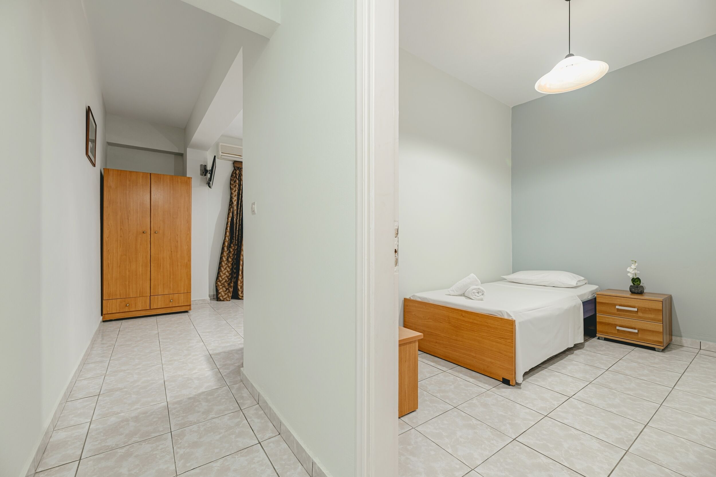 Een slaapkamer met een bed, nachtkastje en een kledingkast.