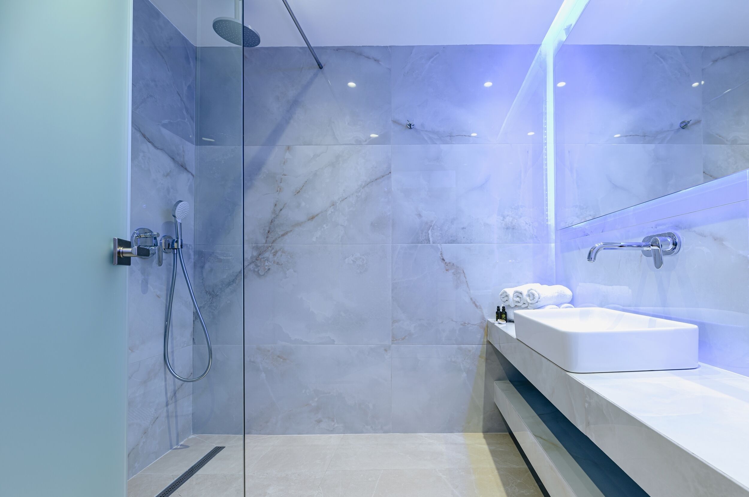 A modern bathroom with a glass-enclosed shower, a white sink, and a mirror.