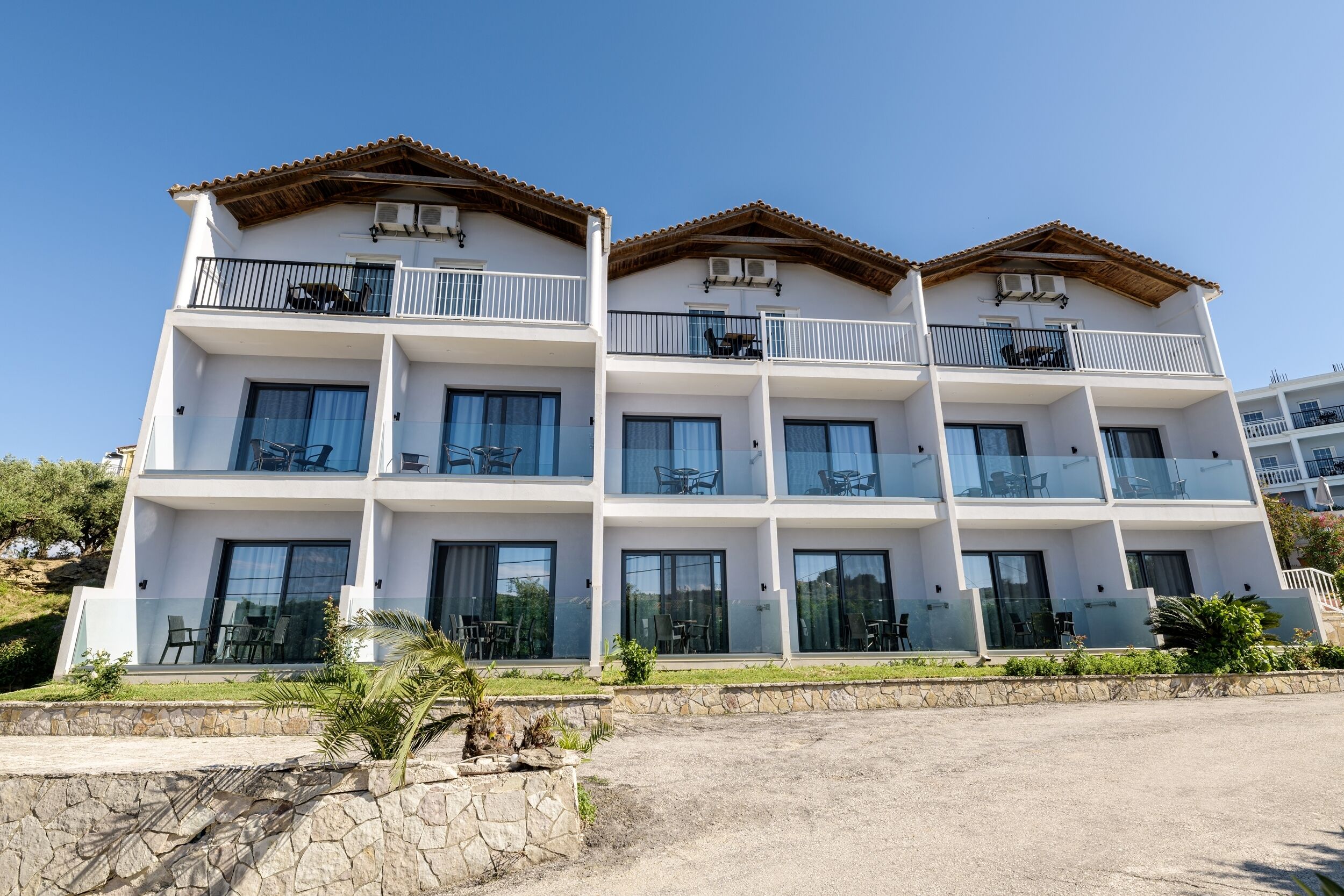 A multi-story hotel with balconies, large windows, and outdoor seating areas.
