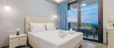 A modern hotel room with a large bed, a nightstand, a dresser, and a view of the city through a large window.